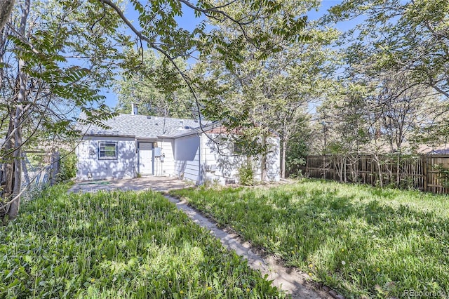 rear view of house featuring a patio area, a fenced backyard, and roof with shingles