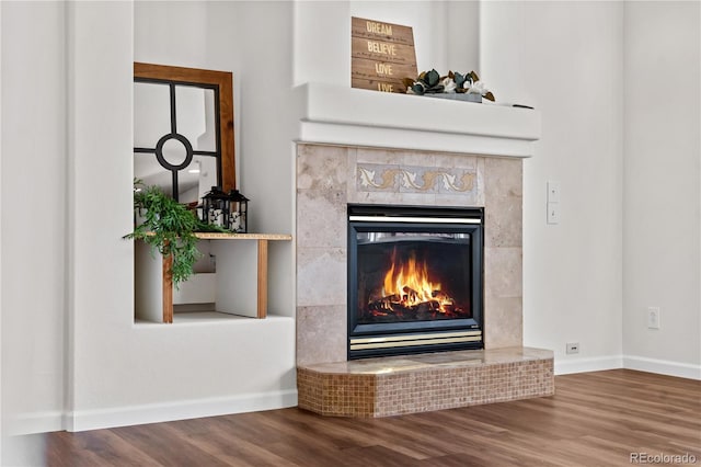 details featuring a tile fireplace and hardwood / wood-style flooring