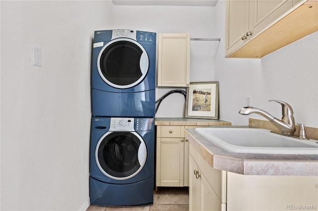 laundry room with sink, light tile patterned flooring, cabinets, and stacked washer and dryer