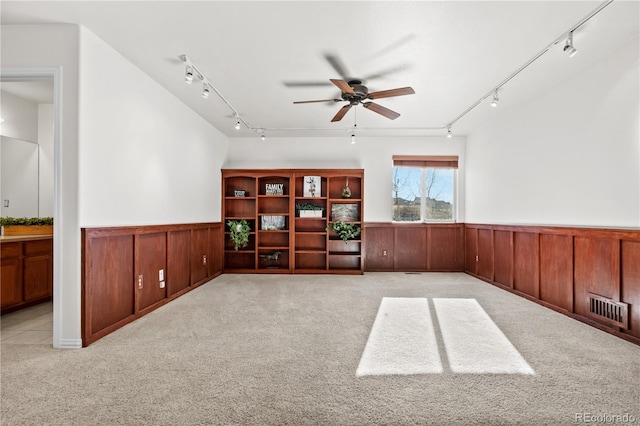 unfurnished room featuring light colored carpet, ceiling fan, and wooden walls