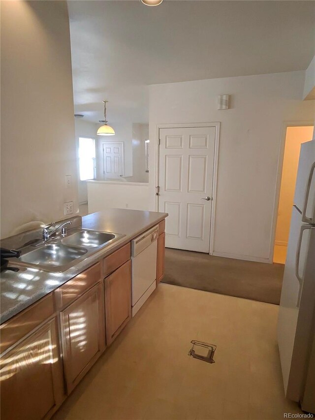 kitchen featuring white appliances, pendant lighting, brown cabinetry, and a sink