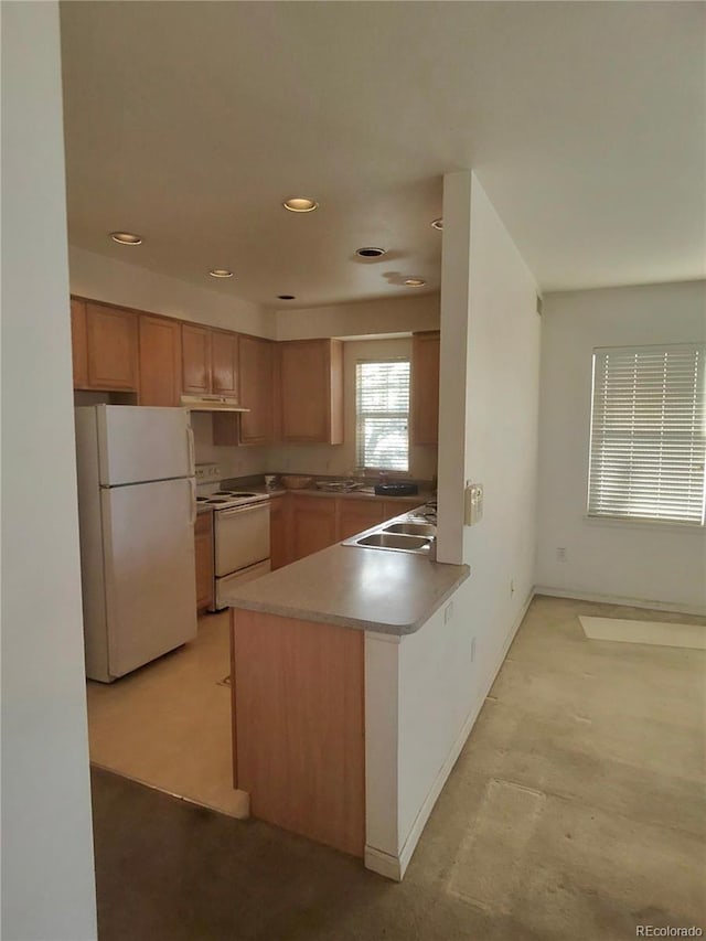 kitchen featuring baseboards, under cabinet range hood, a peninsula, white appliances, and a sink