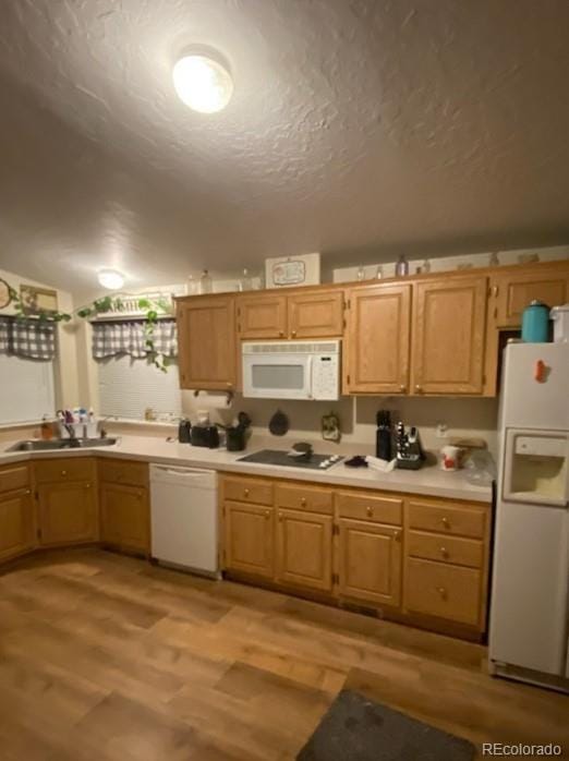 kitchen featuring light wood-type flooring, white appliances, a textured ceiling, sink, and light brown cabinets