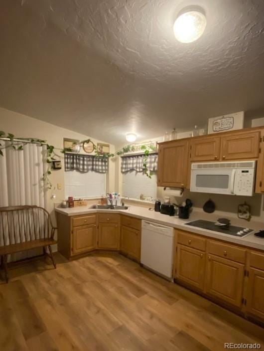 kitchen with sink, light hardwood / wood-style flooring, a textured ceiling, vaulted ceiling, and white appliances