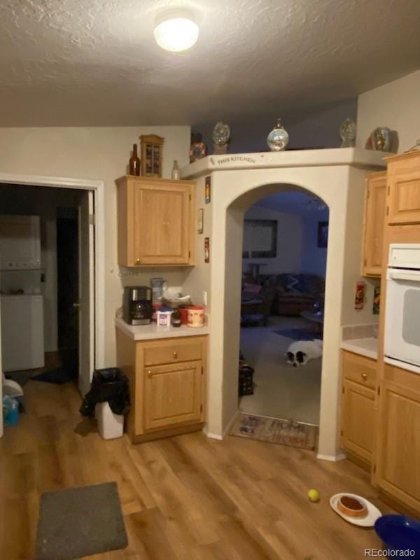 kitchen with light brown cabinets, light hardwood / wood-style floors, and oven