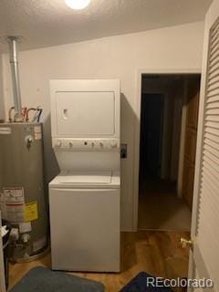 laundry room featuring wood-type flooring, stacked washer and dryer, and water heater