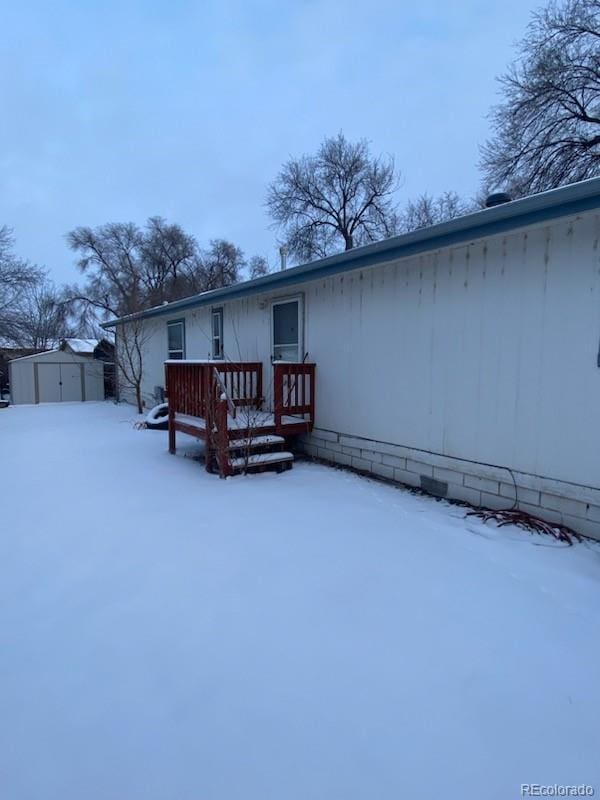 snow covered house featuring a shed