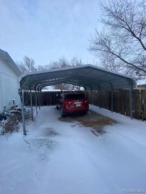 snow covered parking area with a carport