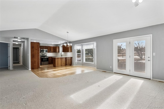 kitchen featuring pendant lighting, light colored carpet, appliances with stainless steel finishes, and a notable chandelier