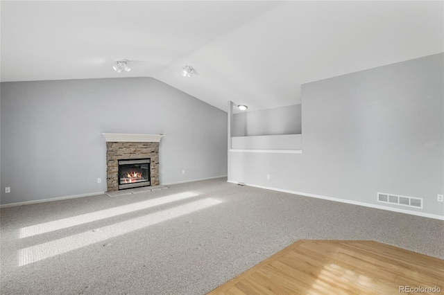 unfurnished living room featuring vaulted ceiling, carpet flooring, and a fireplace