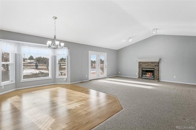 unfurnished living room with lofted ceiling, an inviting chandelier, light carpet, and a fireplace