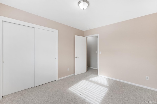 unfurnished bedroom with light colored carpet and a closet