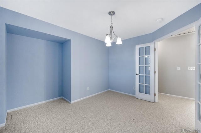 carpeted spare room with a chandelier and baseboards