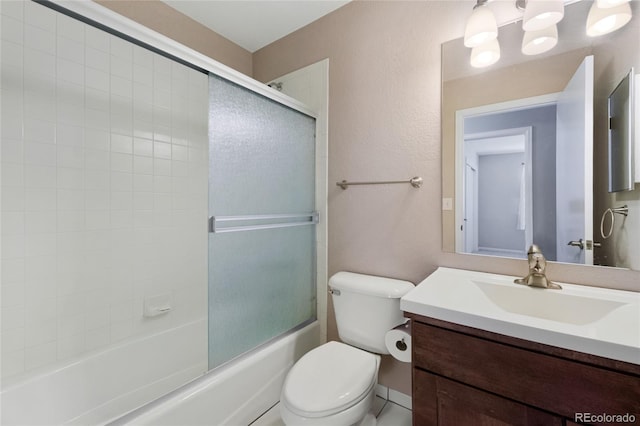 bathroom with vanity, toilet, a textured wall, and combined bath / shower with glass door