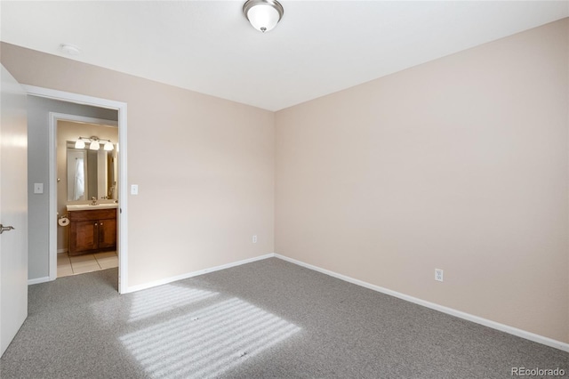 empty room featuring baseboards, carpet, and a sink