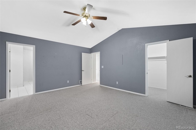 unfurnished bedroom with a spacious closet, ceiling fan, lofted ceiling, carpet flooring, and ensuite bath