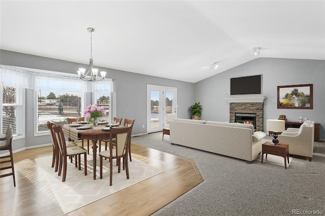 dining room with baseboards, an inviting chandelier, a fireplace, and vaulted ceiling