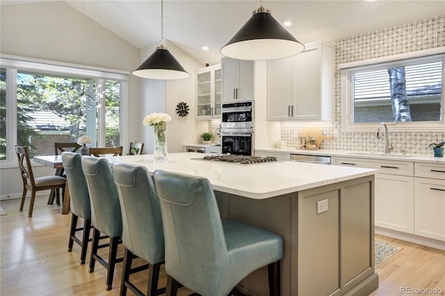 74 Blue Heron Dr, Greenwood Village, CO 80121 - kitchen featuring a center island, appliances with stainless steel finishes, backsplash, a kitchen bar, and glass insert cabinets