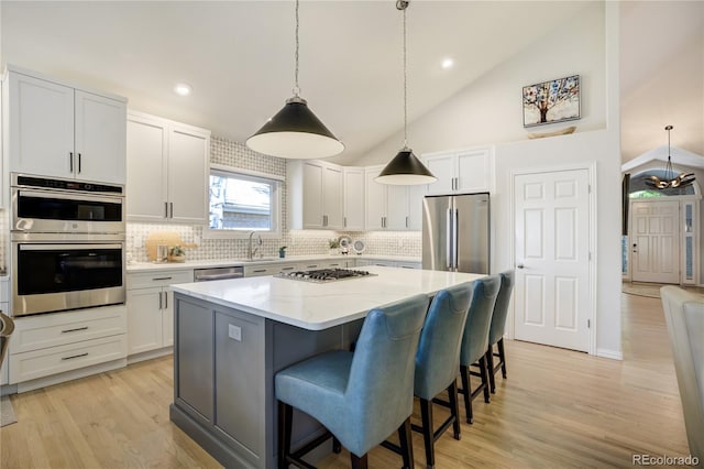 74 Blue Heron Dr, Greenwood Village, CO 80121 - kitchen featuring stainless steel appliances, a kitchen island, decorative backsplash, light stone countertops, and light wood-style flooring