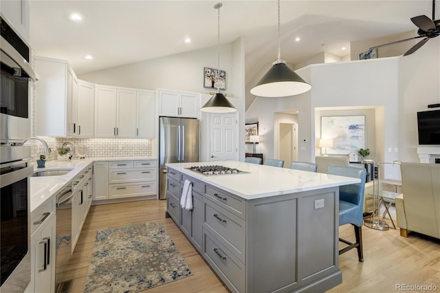 74 Blue Heron Dr, Greenwood Village, CO 80121 - kitchen with gray cabinets, a breakfast bar, backsplash, a ceiling fan, and appliances with stainless steel finishes