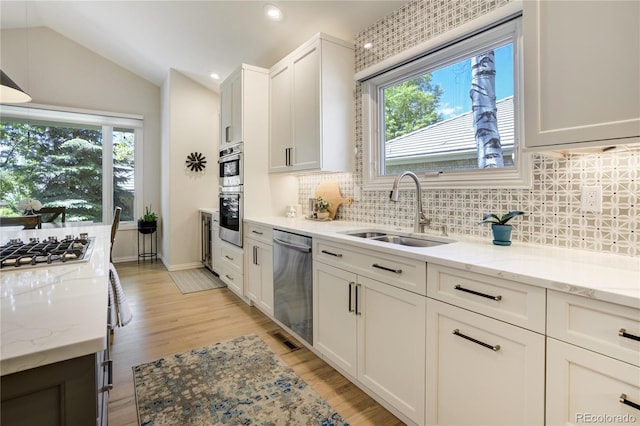 74 Blue Heron Dr, Greenwood Village, CO 80121 - kitchen with appliances with stainless steel finishes, plenty of natural light, light wood-type flooring, backsplash, and lofted ceiling
