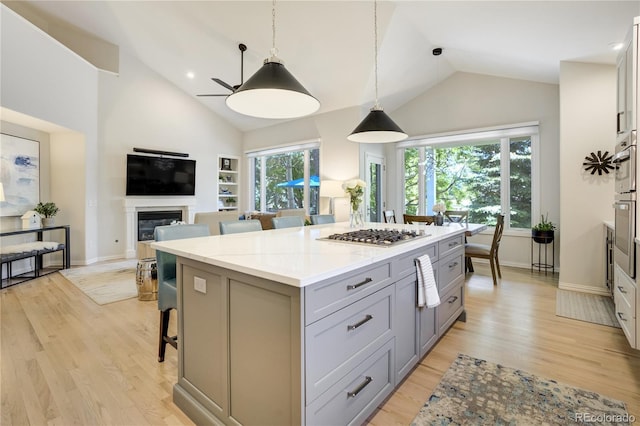 74 Blue Heron Dr, Greenwood Village, CO 80121 - kitchen featuring gray cabinets, stainless steel gas cooktop, a center island, light wood-style flooring, and high vaulted ceiling