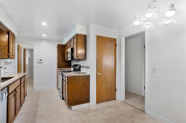 1637 S Stuart St, Denver, CO 80219 - kitchen with stainless steel appliances, a chandelier, brown cabinets, light stone counters, and recessed lighting