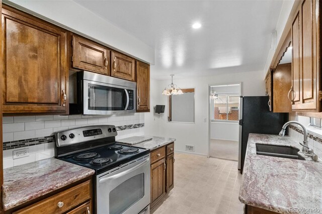 1637 S Stuart St, Denver, CO 80219 - kitchen with stainless steel appliances, backsplash, brown cabinets, and light stone countertops