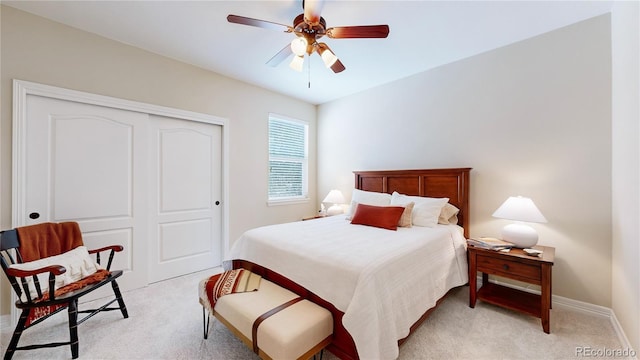 bedroom with light colored carpet, ceiling fan, and a closet