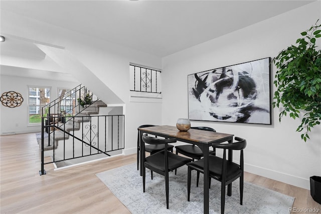 dining area featuring baseboards, wood finished floors, and stairway