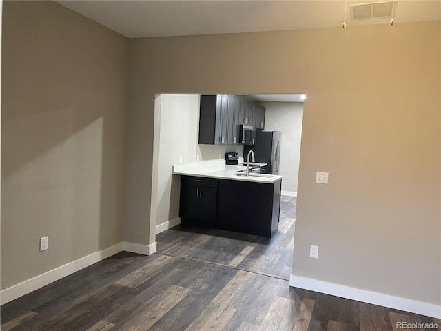 kitchen with appliances with stainless steel finishes, kitchen peninsula, sink, and dark hardwood / wood-style floors