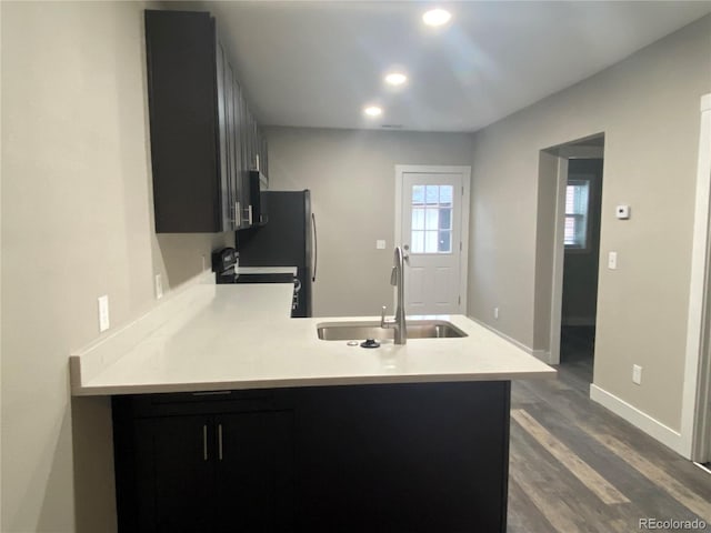 kitchen with black stove, hardwood / wood-style floors, sink, and kitchen peninsula