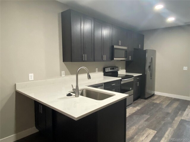 kitchen with dark hardwood / wood-style flooring, kitchen peninsula, stainless steel appliances, and sink