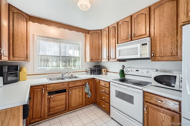 kitchen featuring light tile patterned floors, white appliances, and sink