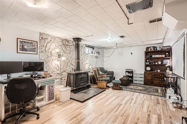 office space with light hardwood / wood-style flooring and a wood stove