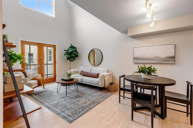 living area with light wood-style floors, a high ceiling, and french doors