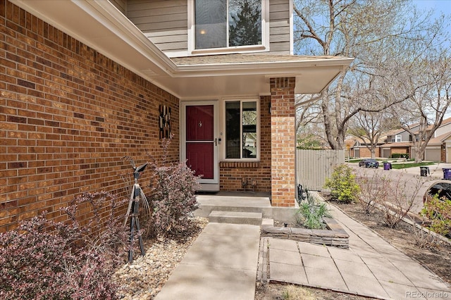 doorway to property featuring brick siding and fence