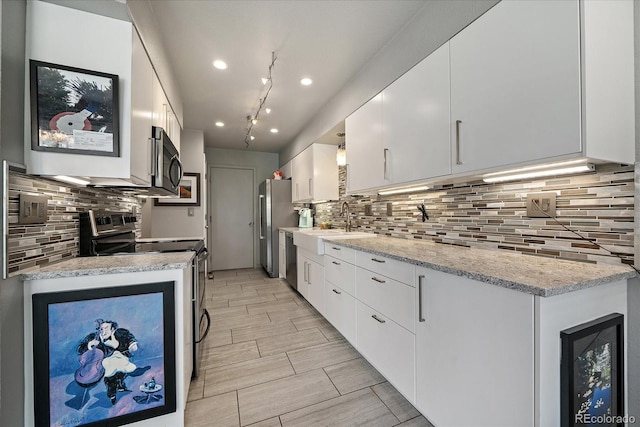 kitchen with a sink, appliances with stainless steel finishes, white cabinets, and tasteful backsplash