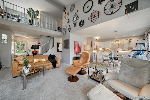 living room featuring carpet, a towering ceiling, a chandelier, and stairway