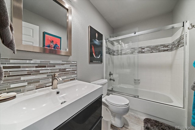 full bathroom featuring backsplash, wood finished floors, vanity, combined bath / shower with glass door, and toilet