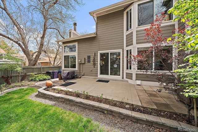 back of house with a patio area, fence, and a chimney