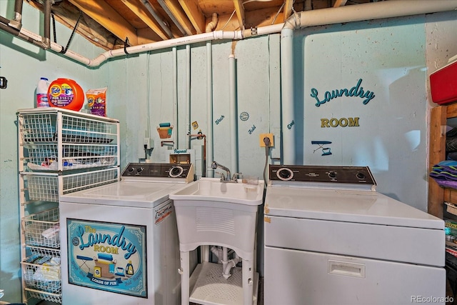 clothes washing area featuring separate washer and dryer, laundry area, and a sink