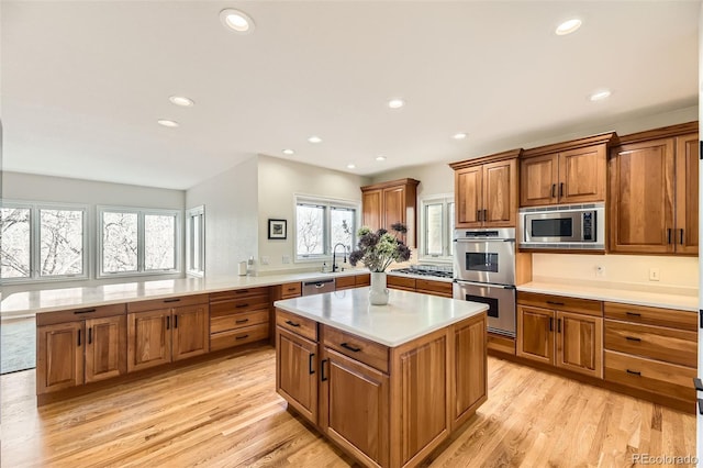 kitchen with stainless steel appliances, sink, a center island, and light hardwood / wood-style floors