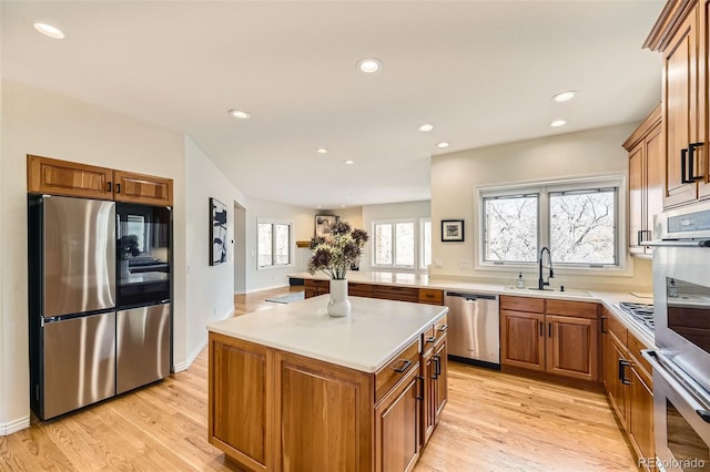 kitchen with light wood-type flooring, sink, a kitchen island, and appliances with stainless steel finishes