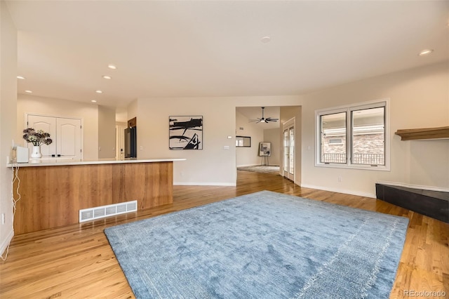 interior space with ceiling fan, light hardwood / wood-style floors, and kitchen peninsula