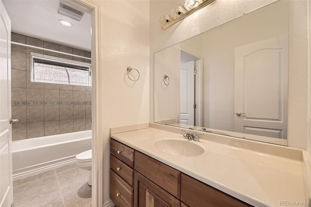 full bathroom featuring tile patterned floors, vanity, toilet, and tiled shower / bath combo