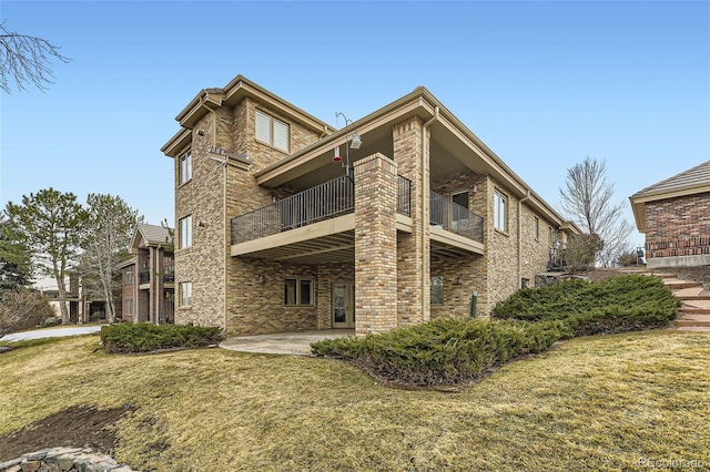 exterior space with a balcony, a patio, and a lawn