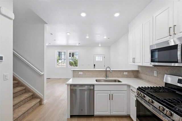 17123 W 91st Ln, Arvada, CO 80007 - kitchen featuring stainless steel appliances, a peninsula, white cabinets, decorative backsplash, and recessed lighting
