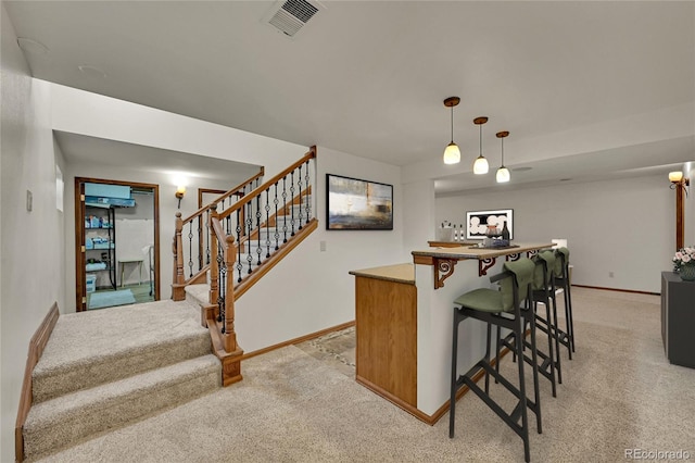 5722 W Chestnut Ave, Littleton, CO 80128 - kitchen with light colored carpet, a kitchen breakfast bar, pendant lighting, and a kitchen island