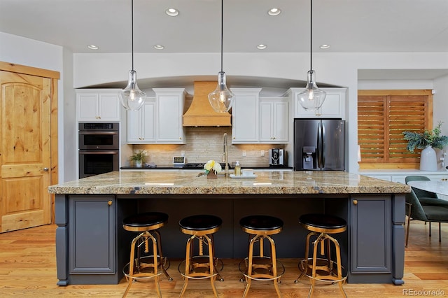 14370 Osage St, Westminster, CO 80023 - kitchen with black fridge with ice dispenser, custom exhaust hood, double oven, white cabinets, and a sink